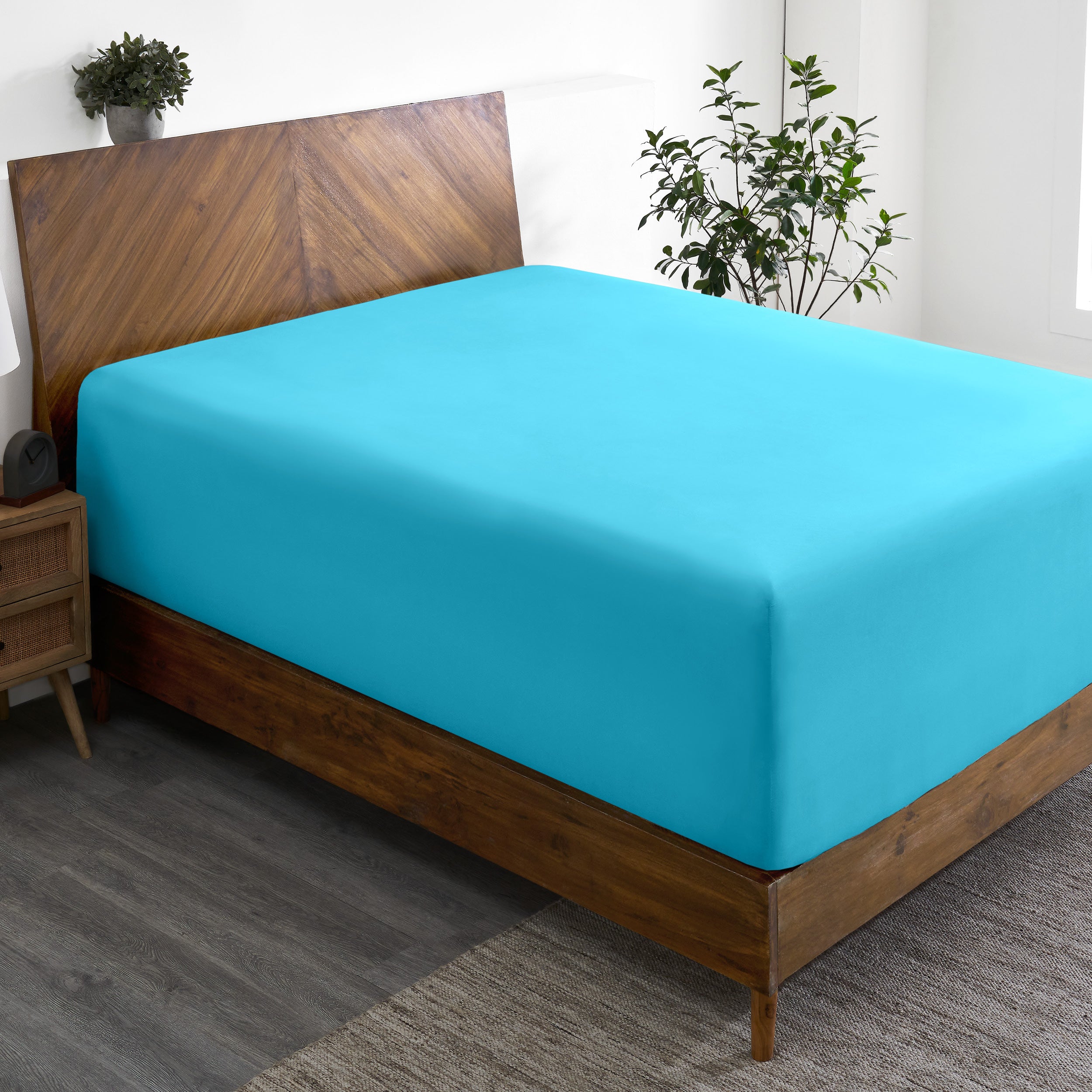 A wide corner view of a modern bed made with a microfiber fitted sheet on the mattress.