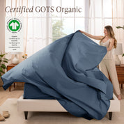 Woman putting bedding on a bed with GOTS Organic certification logo in the corner.