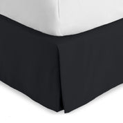 The corner of a bed skirt on a bed frame