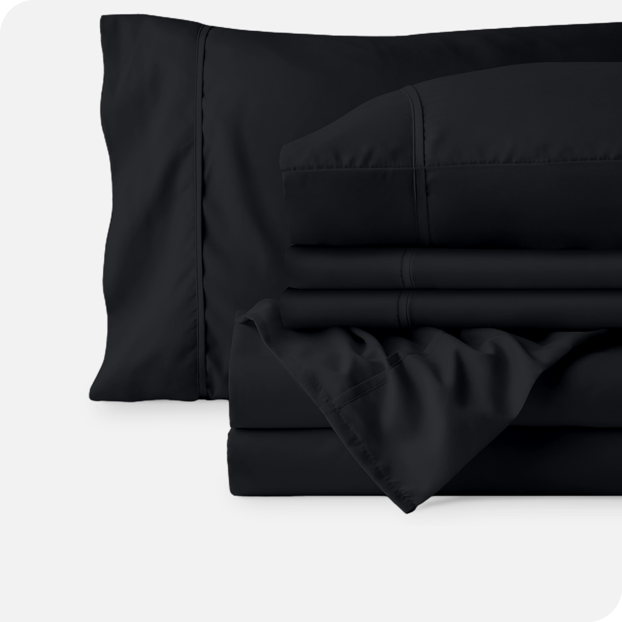Microfiber sheets neatly folded with corner draped over, two folded pillowcases and two display pillows.