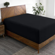 A wide corner view of a modern bed made with a microfiber fitted sheet on the mattress.