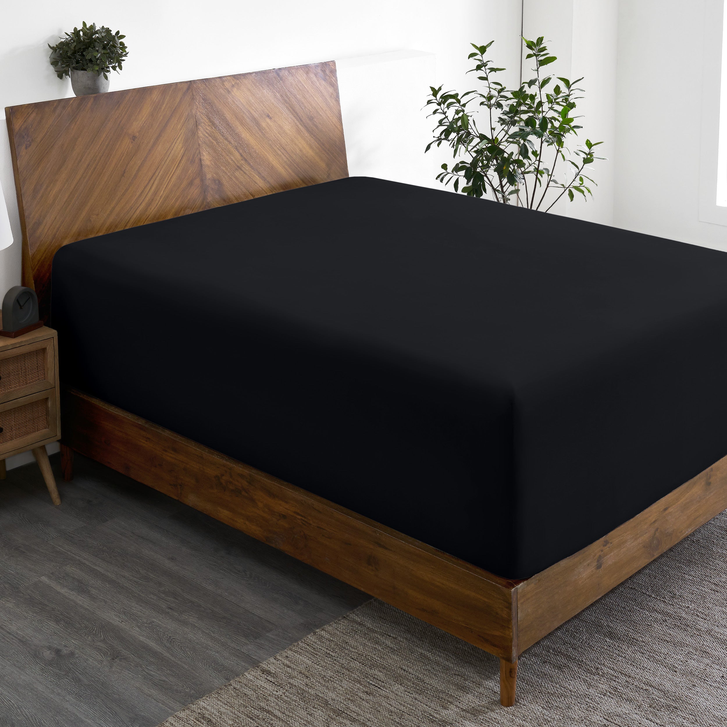 A wide corner view of a modern bed made with a microfiber fitted sheet on the mattress.
