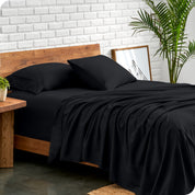 Microfiber sheets and matching pillowcases on a bed next to a large plant