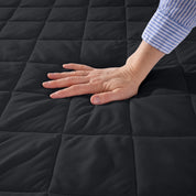 A hand is feeling the texture of the mattress pad.