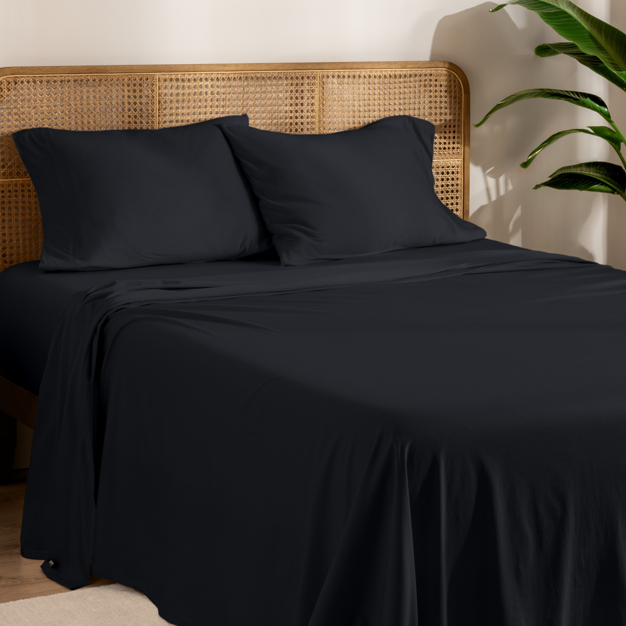 Organic jersey sheets and pillowcases on a bed with plants on the side in a bright and chill room scene.