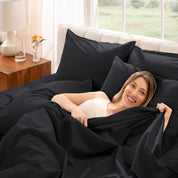 Woman lying in bed under percale sheets with a bright room setting