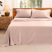 TENCEL™ sheet set on a bed with the flat sheet loosely draped over the top. The mattress is on a wooden bed frame.