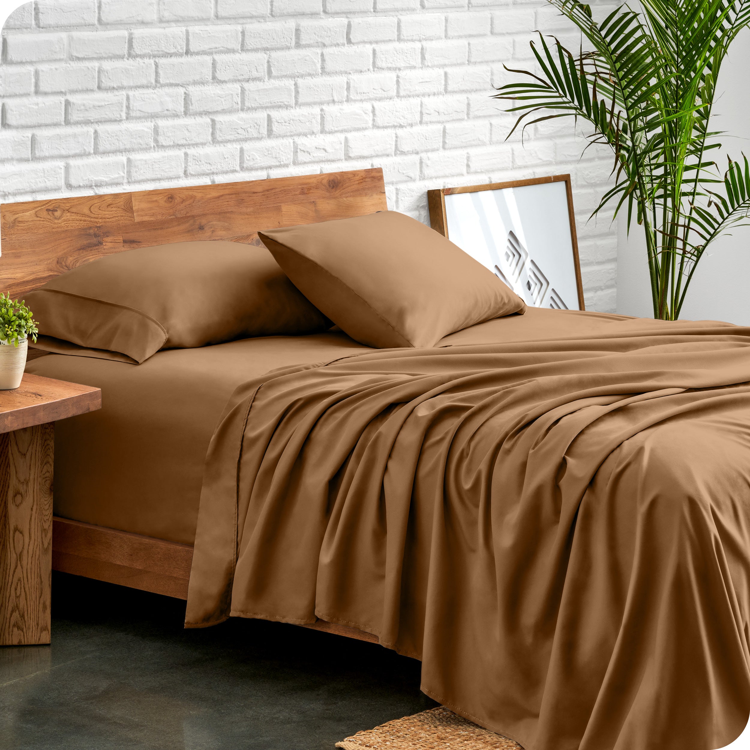 Microfiber sheets and matching pillowcases on a bed next to a large plant