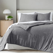 A comforter set on a bed in a bright modern room