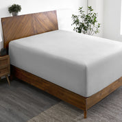 A wide corner view of a modern bed made with a microfiber fitted sheet on the mattress.