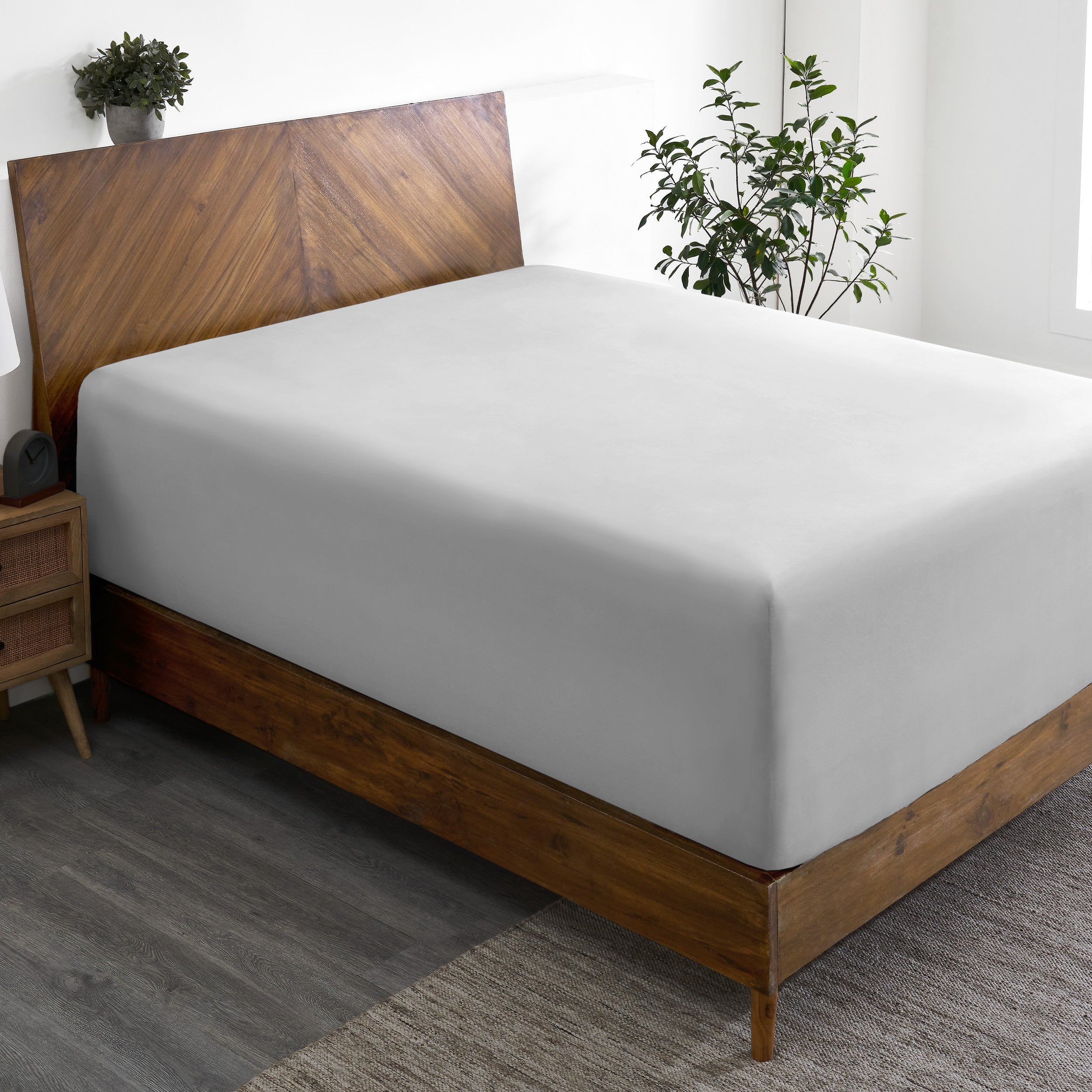 A wide corner view of a modern bed made with a microfiber fitted sheet on the mattress.