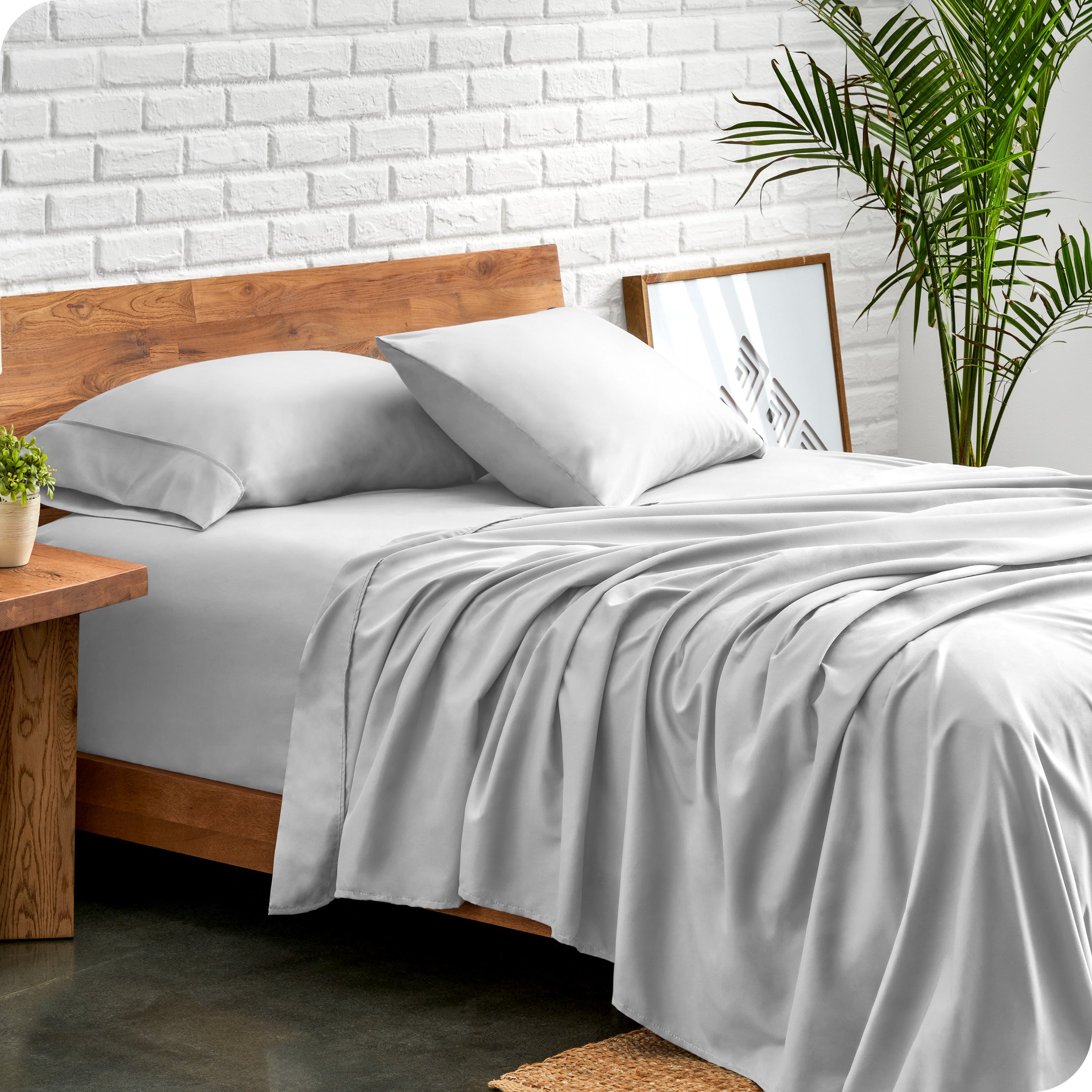 Microfiber sheets and matching pillowcases on a bed next to a large plant