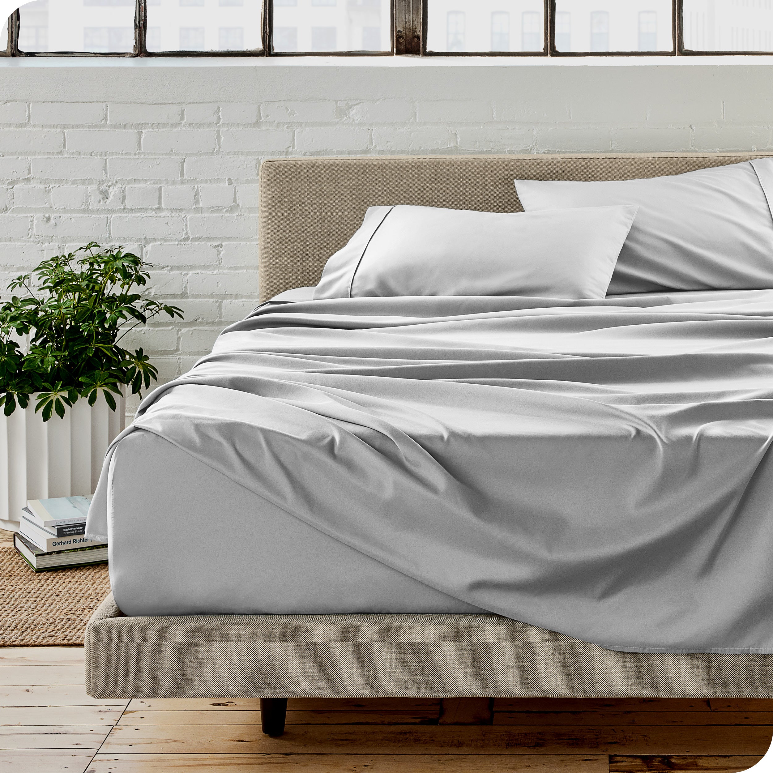 Microfiber sheets on a bed with a brick wall behind it