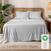 A bed in the middle of room with a set of Certified GOTS Organic Jersey Sheet Set on it.