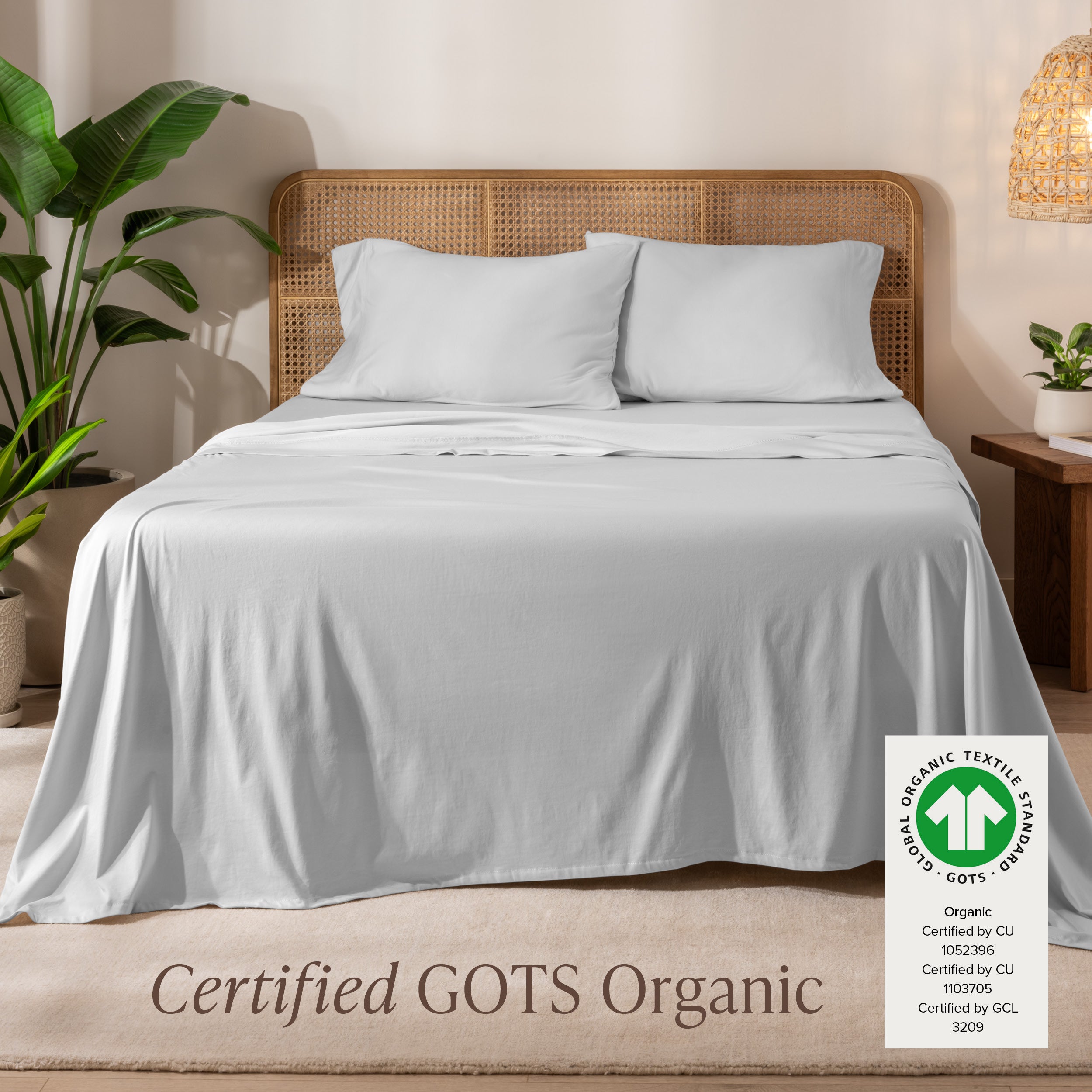 A bed in the middle of room with a set of Certified GOTS Organic Jersey Sheet Set on it.