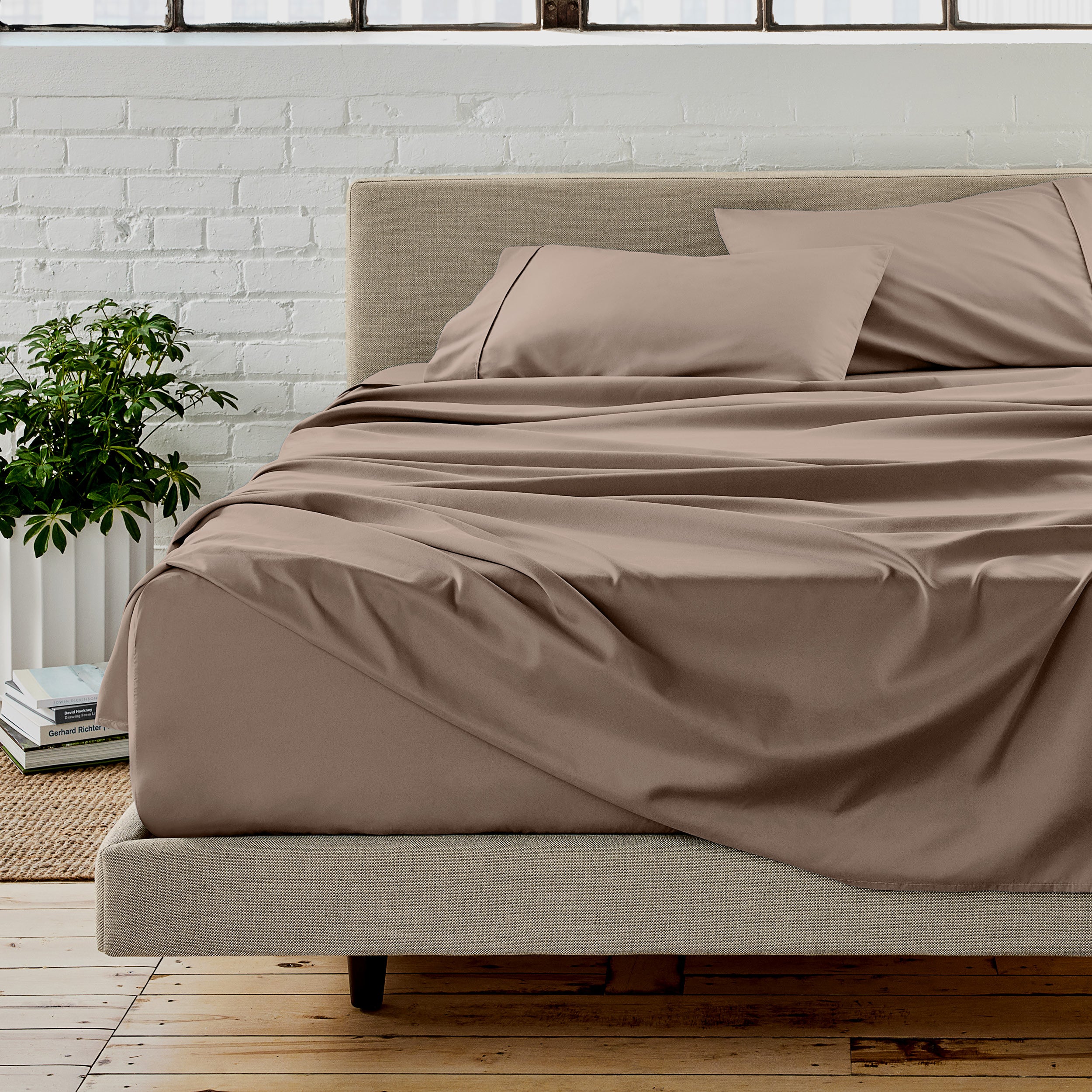 The sheet set with the matched same color pillowcases putting over the bed in a modern room.