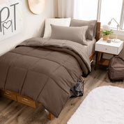 A wooden bed frame with a reversible comforter and sheet set on the mattress in a dorm style room.