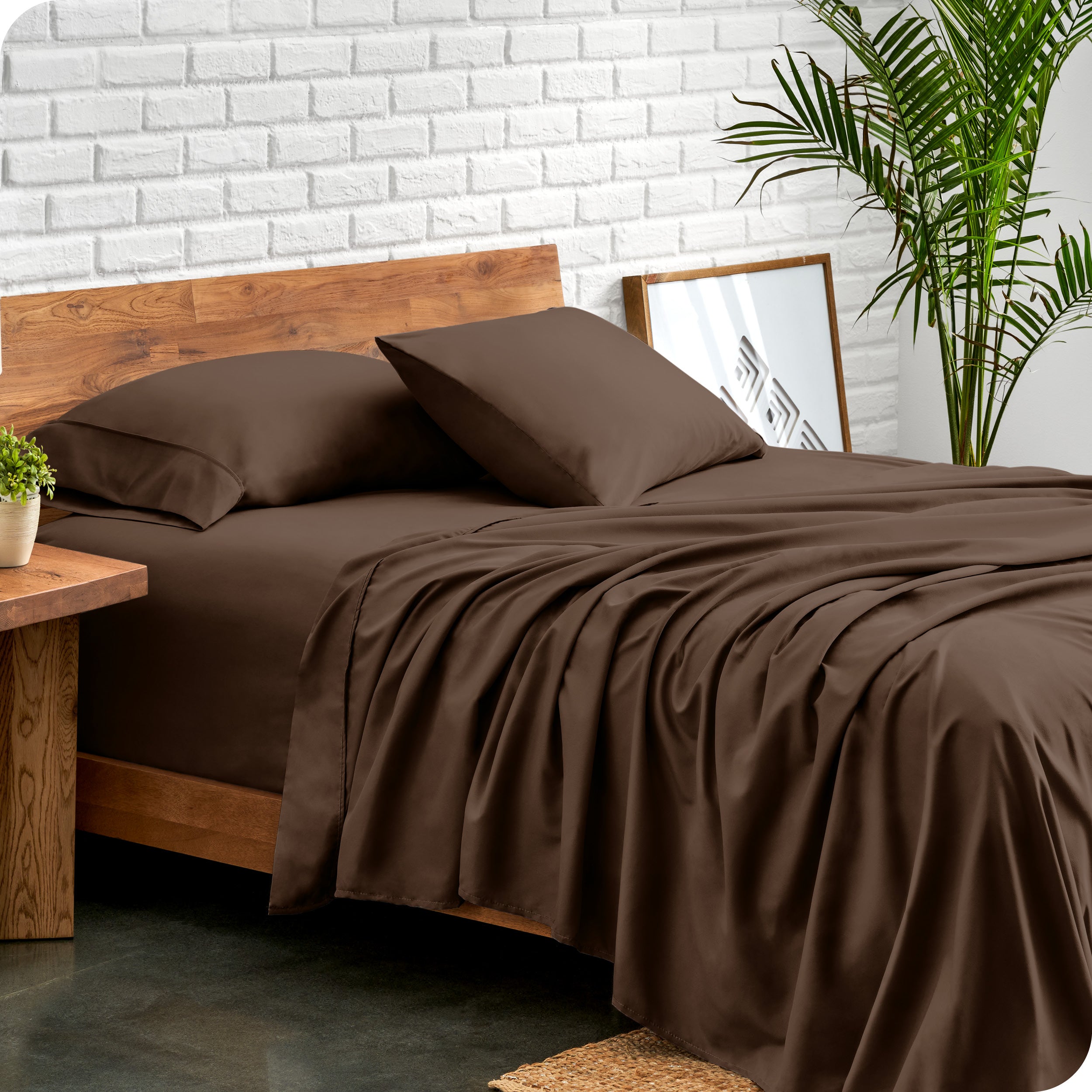 Microfiber sheets and matching pillowcases on a bed next to a large plant