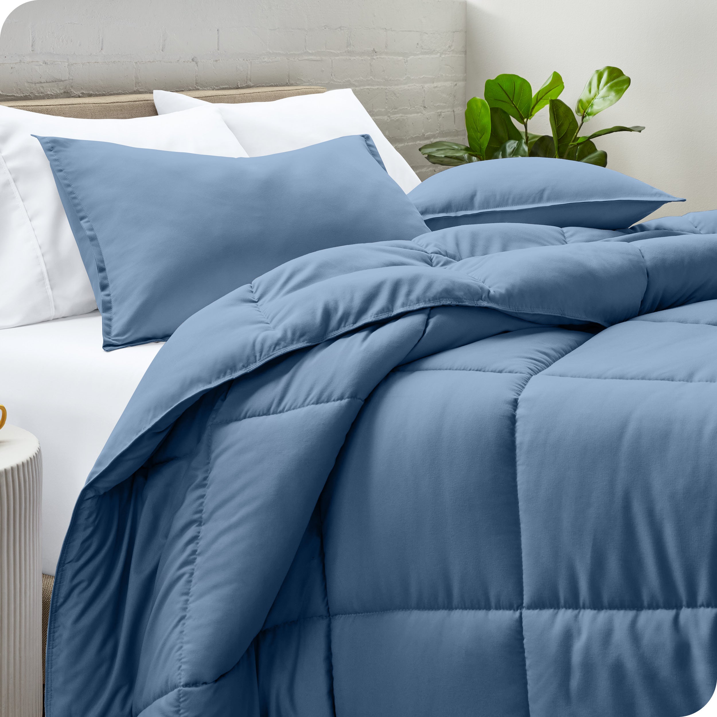 A side view of a modern bed with a comforter set and pillows on the bed