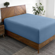 A wide corner view of a modern bed made with a microfiber fitted sheet on the mattress.