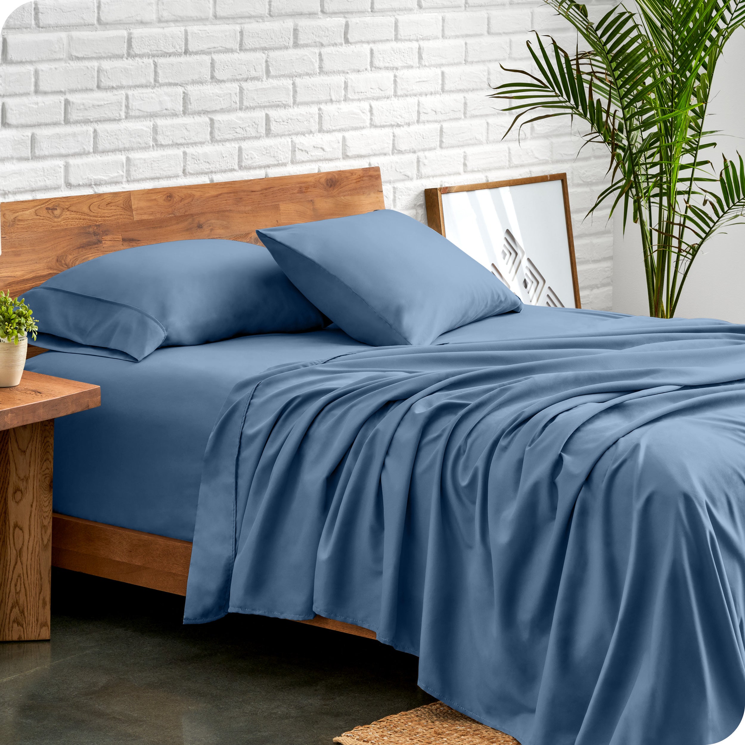Microfiber sheets and matching pillowcases on a bed next to a large plant