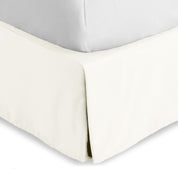 The corner of a bed skirt on a bed frame