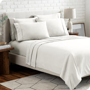 A bedroom setting with a bed made with the microfiber bed sheets and four pillows.