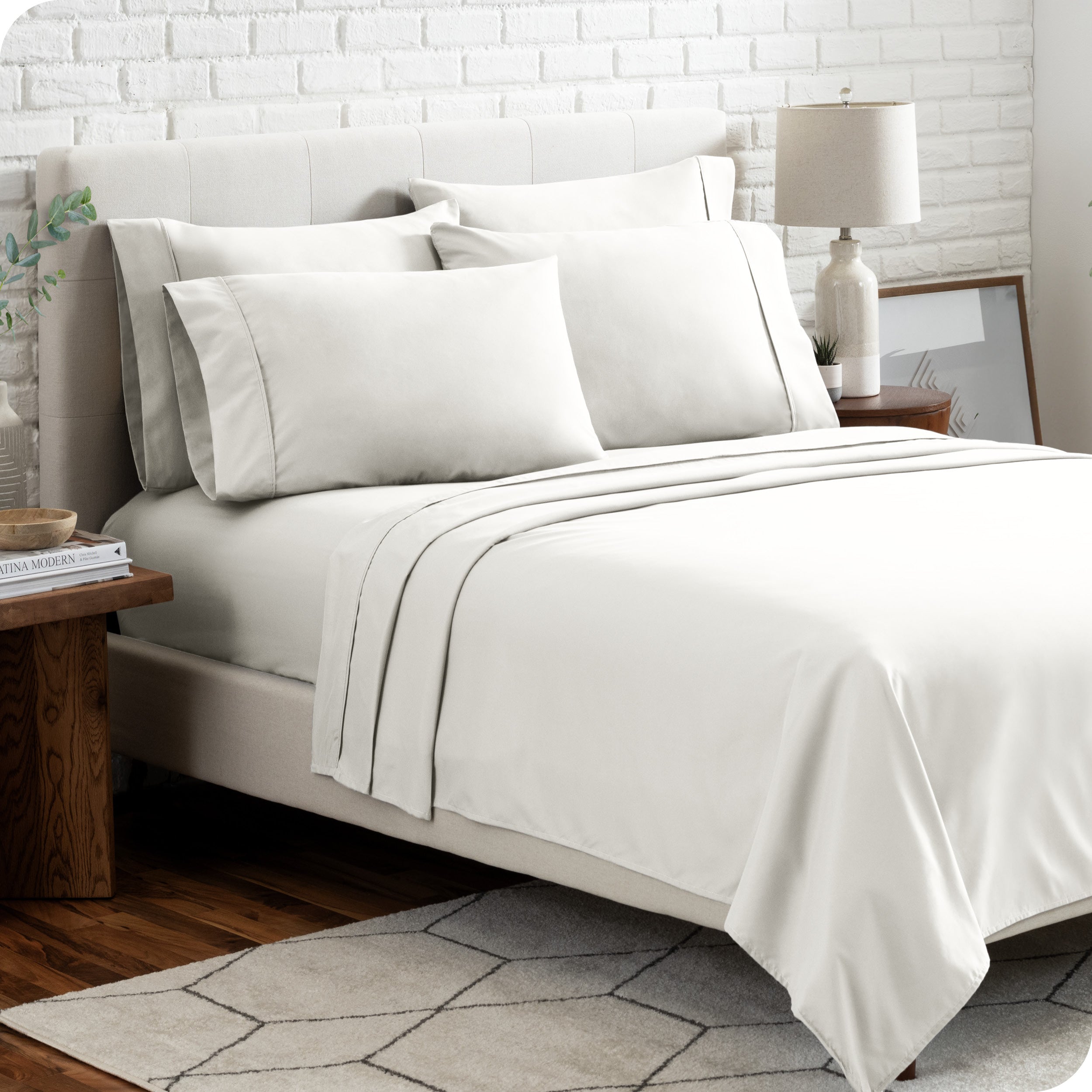 A bedroom setting with a bed made with the microfiber bed sheets and four pillows.