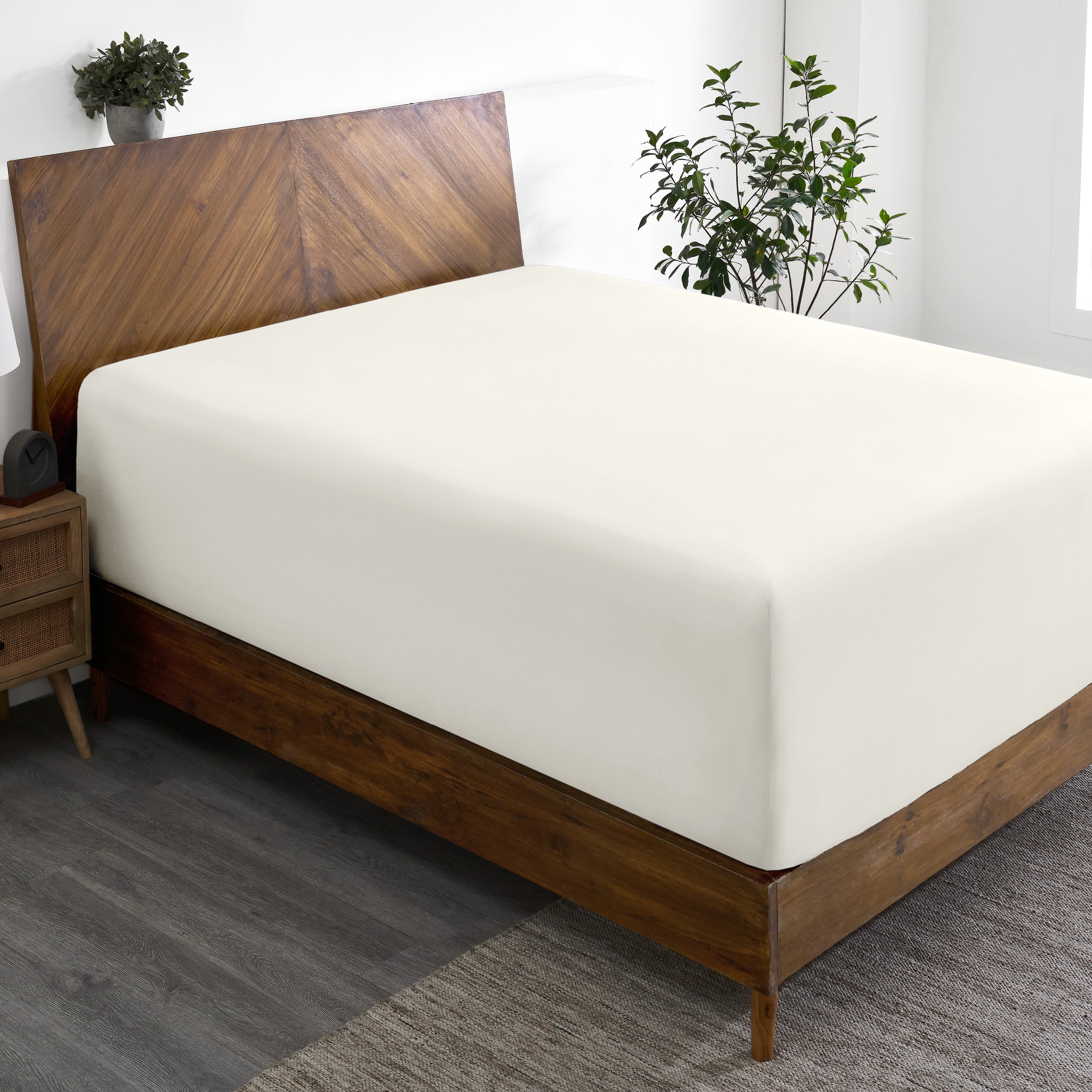 A wide corner view of a modern bed made with a microfiber fitted sheet on the mattress.