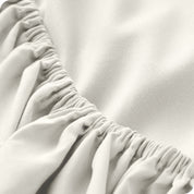 A modern bed with a fitted microfiber sheet on it