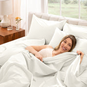Woman lying in bed under percale sheets with a bright room setting