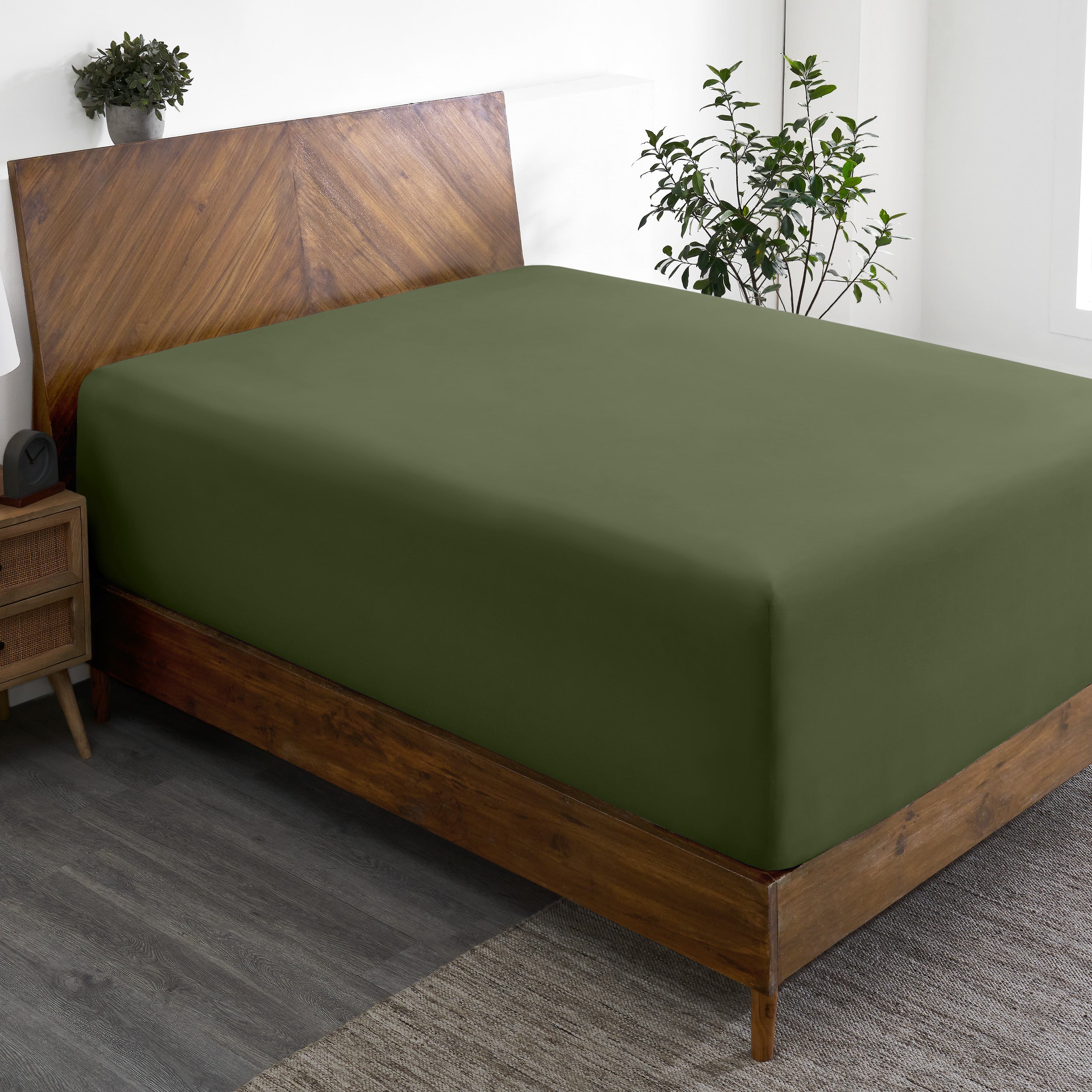 A wide corner view of a modern bed made with a microfiber fitted sheet on the mattress.