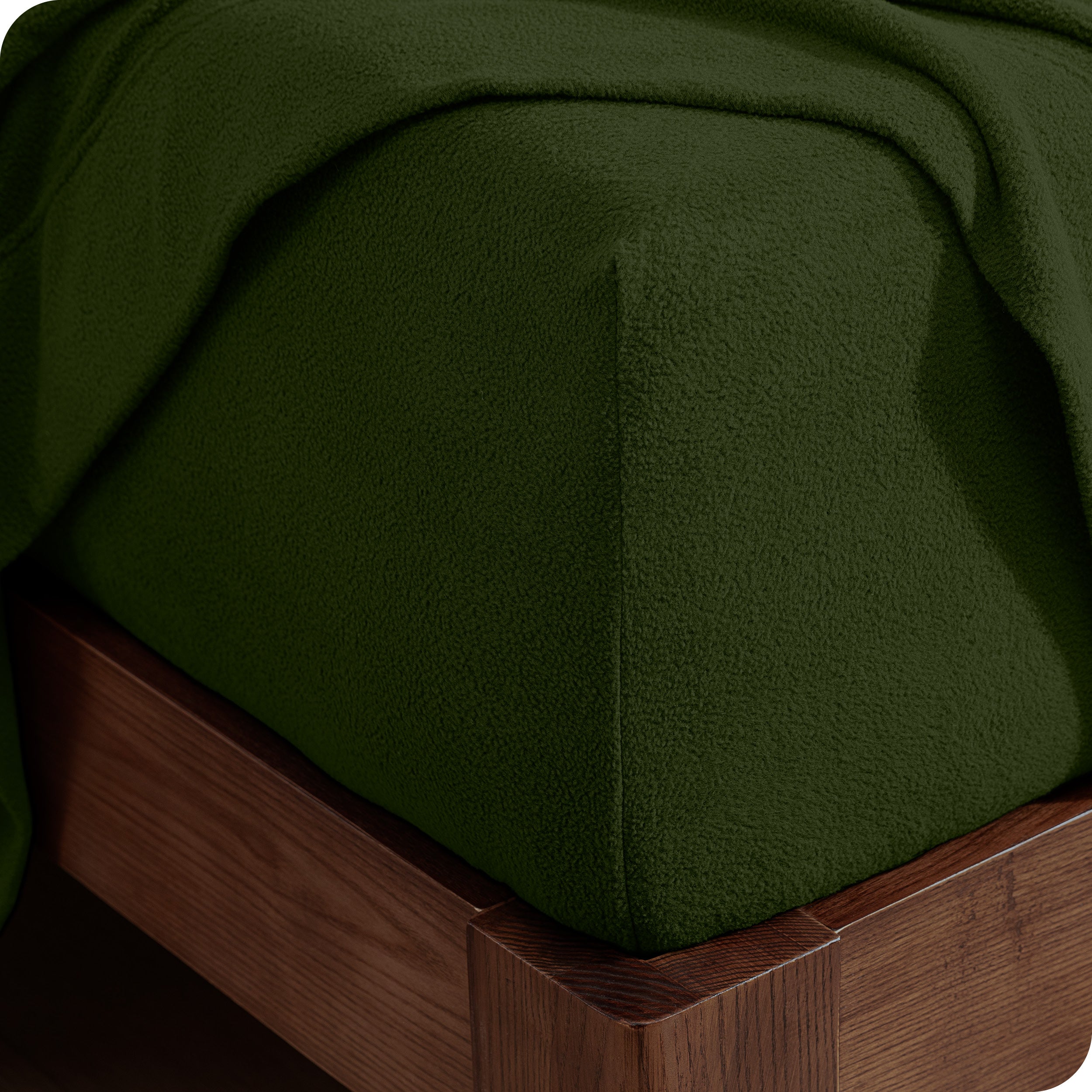 Corner of the bed with a fitted sheet on the mattress and a flat sheet draped over the side and end