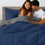 A couple sitting in a bed made with a reversible comforter and sheet set