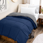 Wooden bed frame with a reversible comforter on the bed. The comforter is folded back over showing the two different colors.