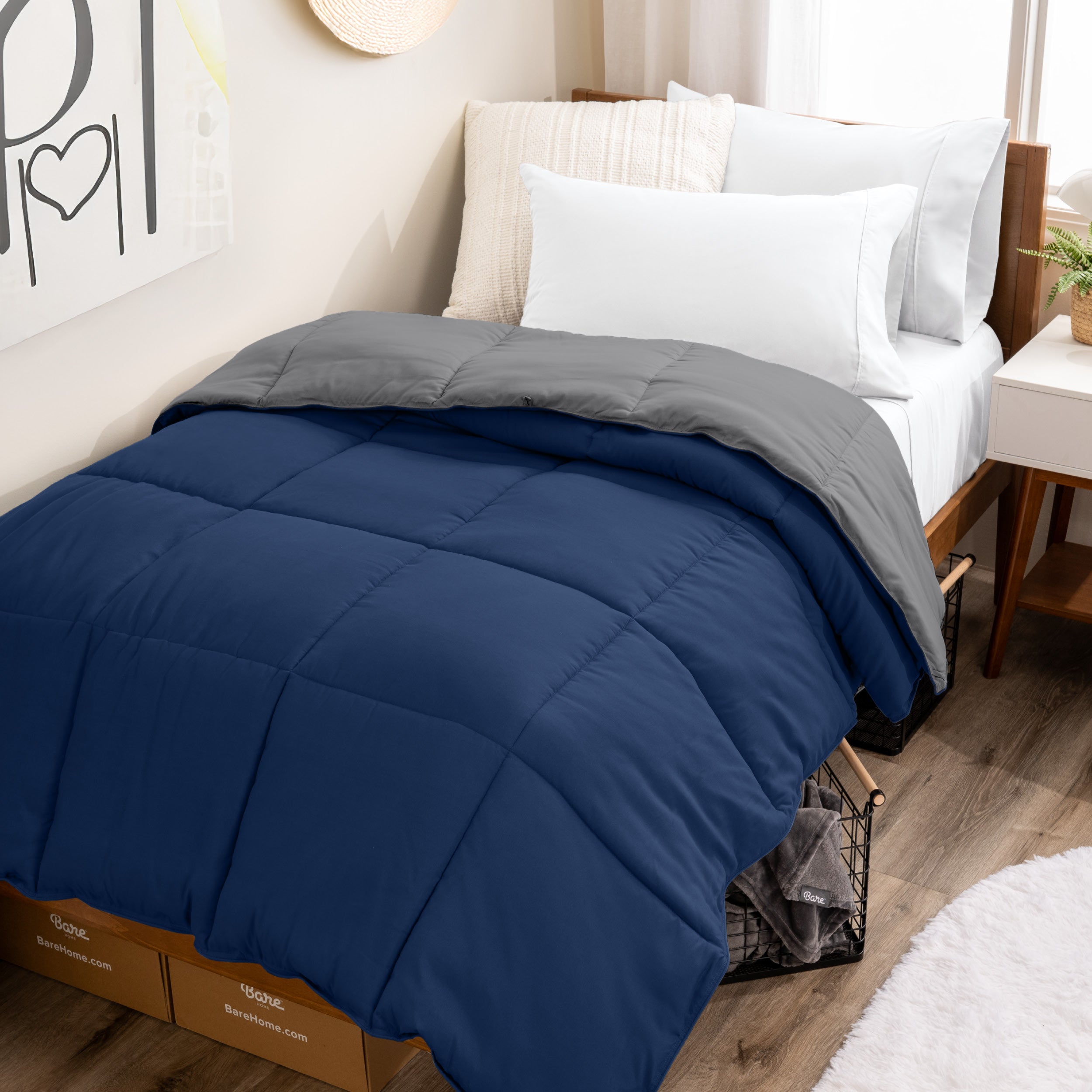 Wooden bed frame with a reversible comforter on the bed. The comforter is folded back over showing the two different colors.