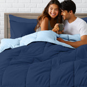 A couple sitting in a bed made with a reversible comforter and sheet set