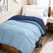Wooden bed frame with a reversible comforter on the bed. The comforter is folded back over showing the two different colors.