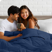 A couple sitting in bed with a comforter over them