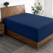 A wide corner view of a modern bed made with a microfiber fitted sheet on the mattress.