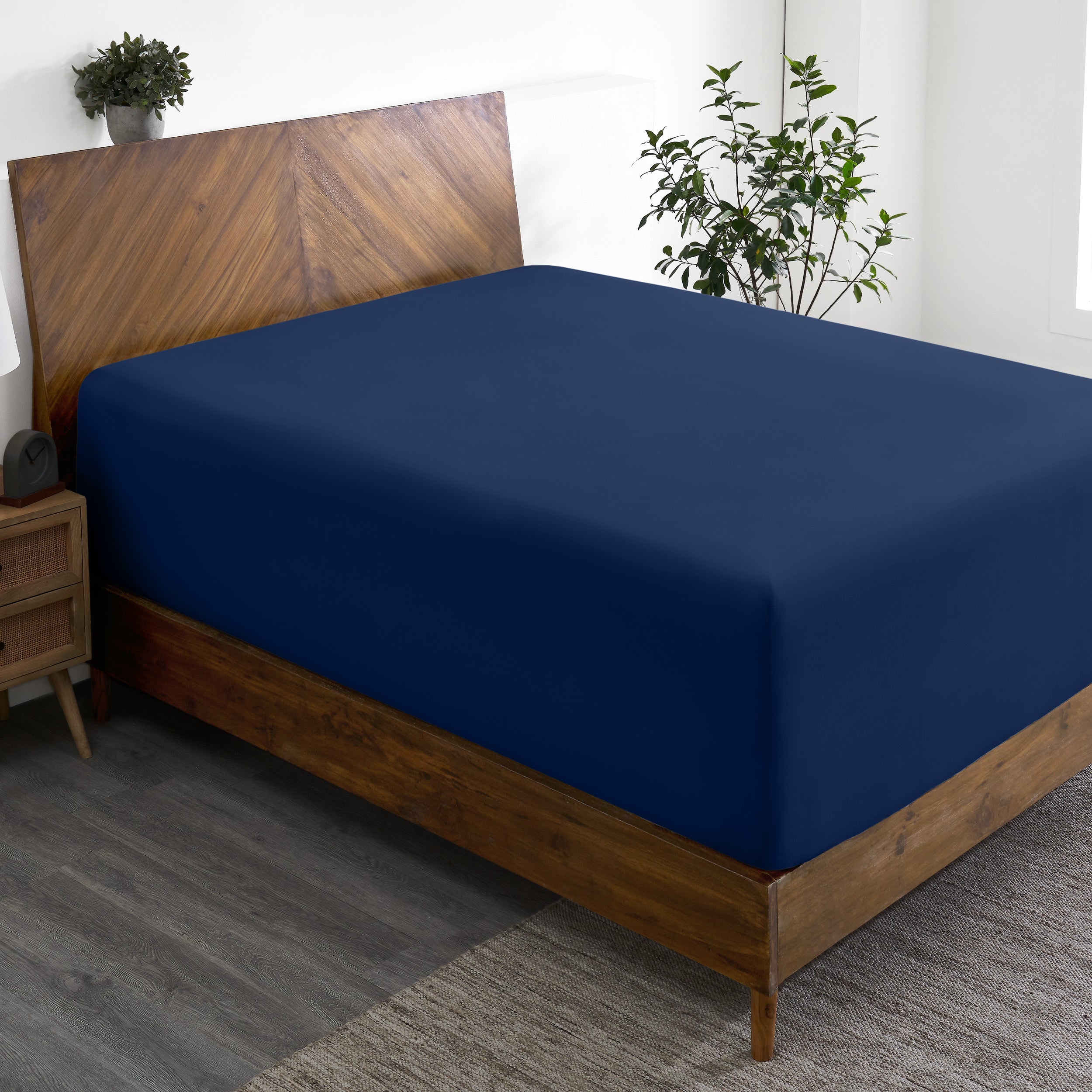 A wide corner view of a modern bed made with a microfiber fitted sheet on the mattress.