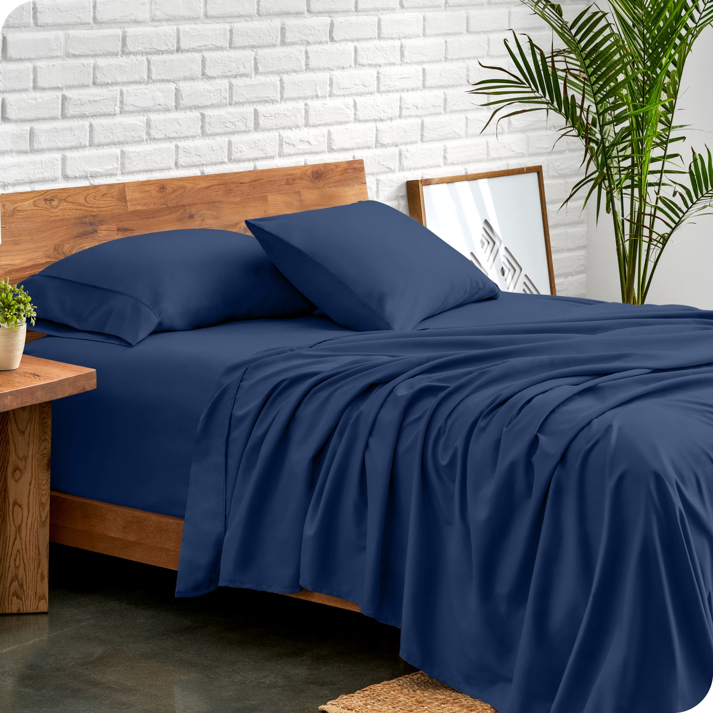 Microfiber sheets and matching pillowcases on a bed next to a large plant