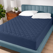 A modern bed with a quilted mattress pad on.