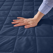 A hand is feeling the texture of the mattress pad.