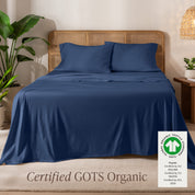 A bed in the middle of room with a set of Certified GOTS Organic Jersey Sheet Set on it.