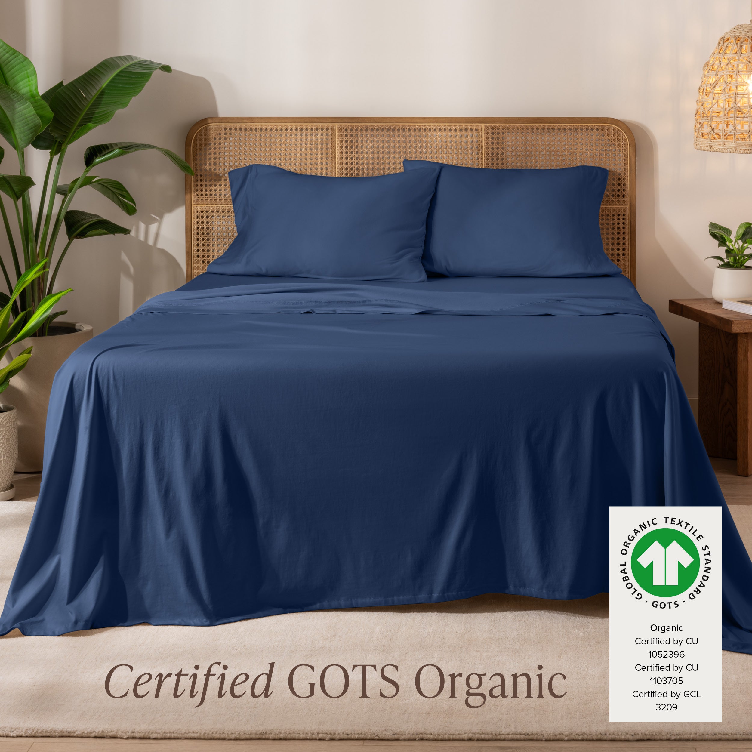 A bed in the middle of room with a set of Certified GOTS Organic Jersey Sheet Set on it.