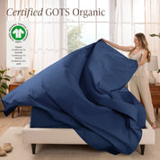 Woman putting bedding on a bed with GOTS Organic certification logo in the corner.