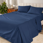 Organic cotton percale sheet set on a bed, with a flat sheet, fitted sheet, and two pillowcases displayed.