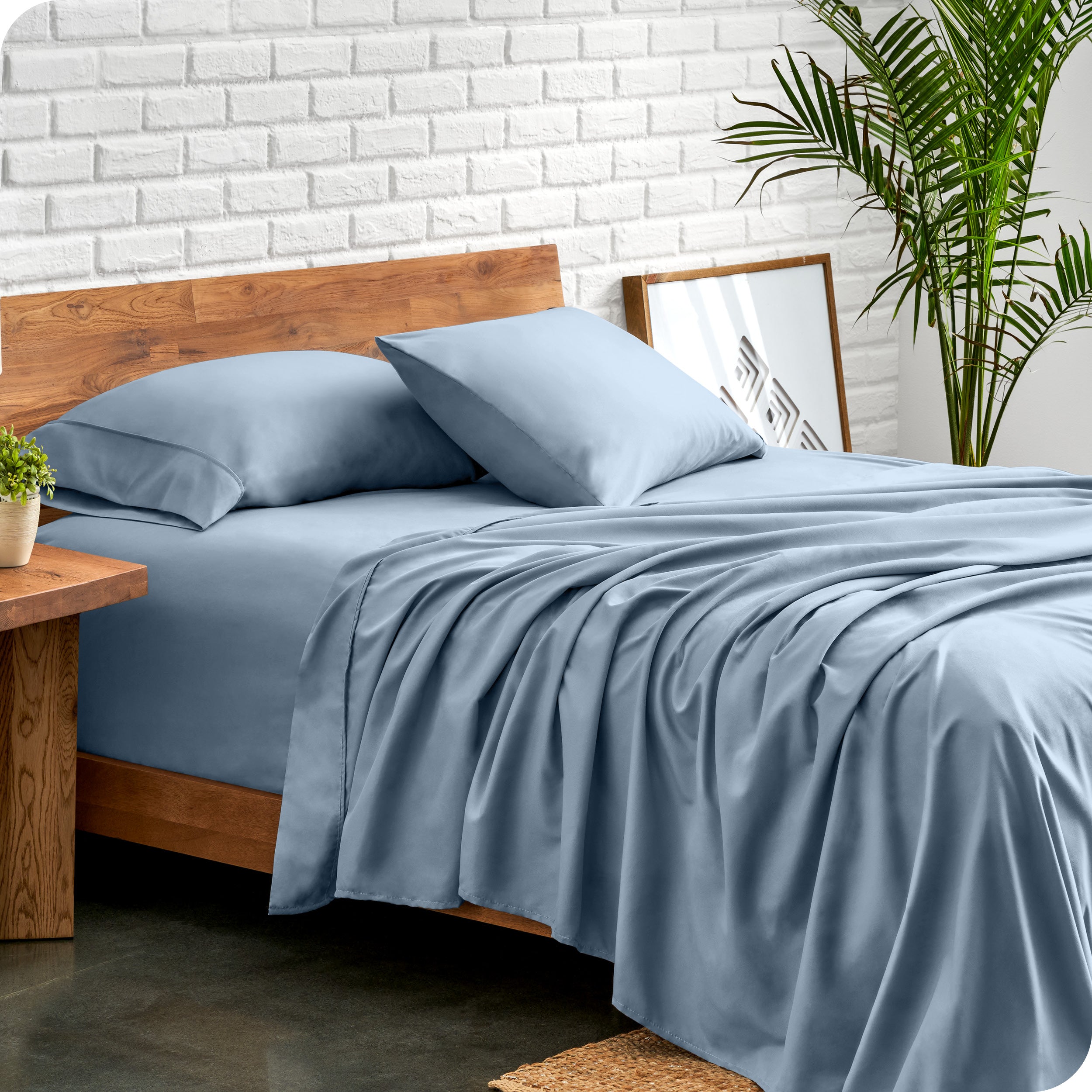 Microfiber sheets and matching pillowcases on a bed next to a large plant