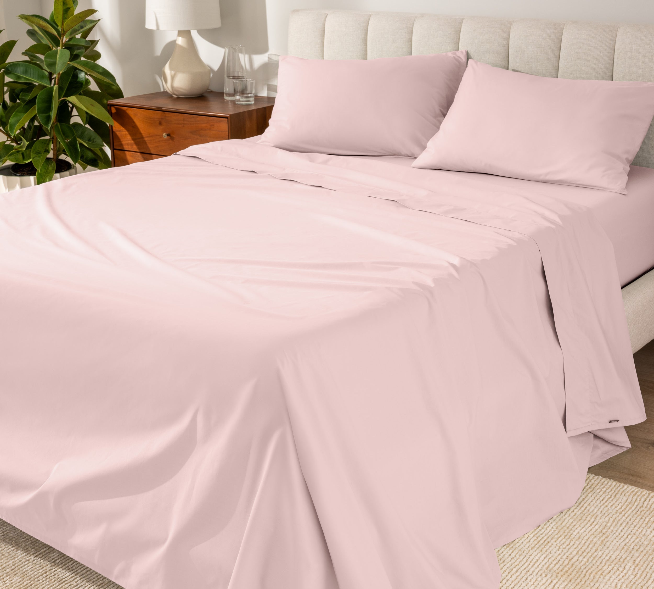 Organic cotton percale sheet set on a bed, with a flat sheet, fitted sheet, and two pillowcases displayed.